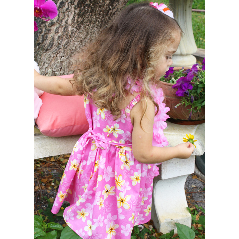 Girls Sweet Leilani bungee Dress – Model sitting with lei and hair flower-back view