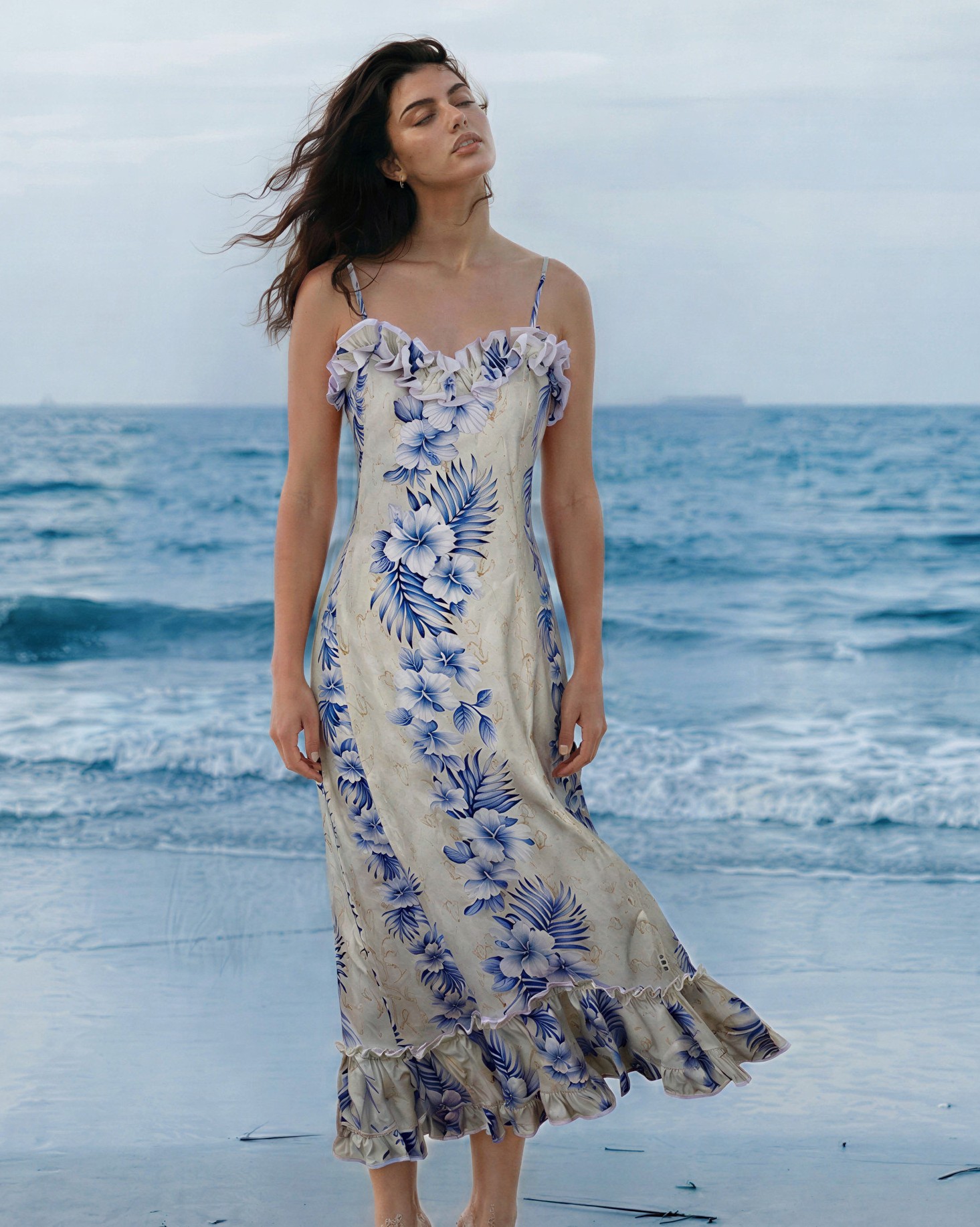 Long-Spaghetti-strap-sundress-Cascade-Sundress-Hawaiian-Hibiscus-Cream-Model-on-the-beach-with-beautiful-blue-waves-crashing-on-beach-behind-her