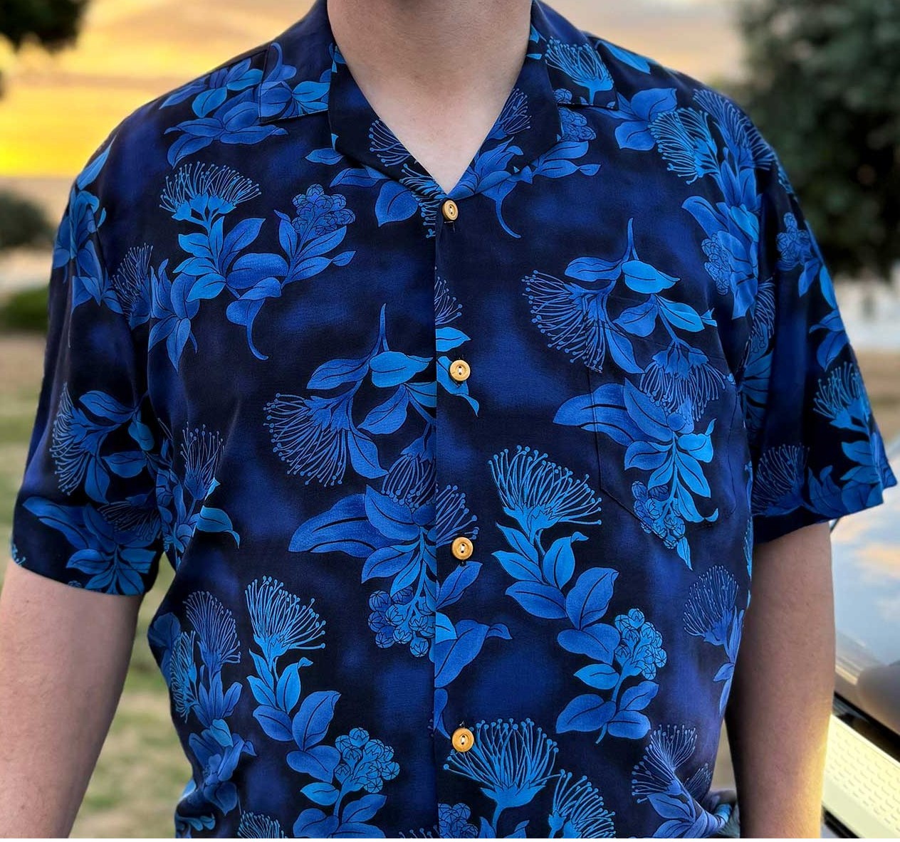 Model-wearing-Mens-Paradise-Found-Hawaiian-Shirt-Ohia-navy-mens-shirt-at-beach-sunrise